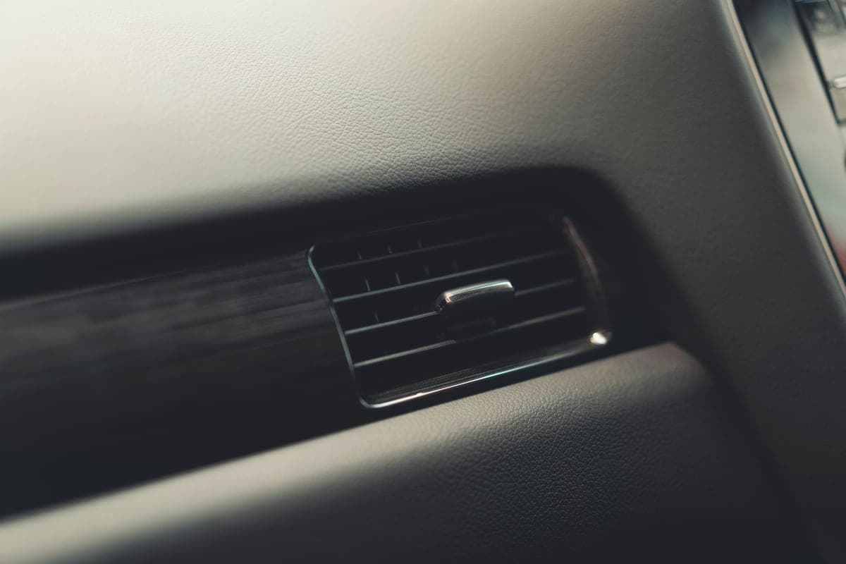 A close-up of the horizontal blades of a car dashboard air vent